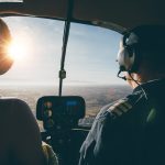 Two pilots in a helicopter while flying on a sunny day. rear view shot of man and woman pilots